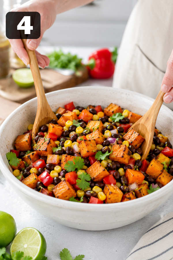 Roasted sweet potato black bean salad being mixed with black beans corn and fresh vegetables