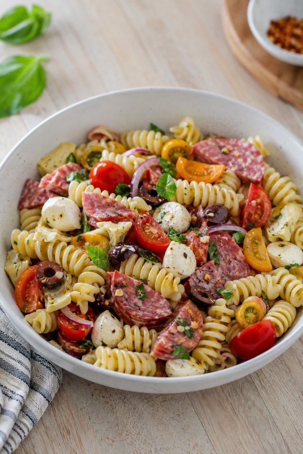 Simple antipasto pasta salad with olives, vegetables, herbs, mozzarella, and tangy vinaigrette