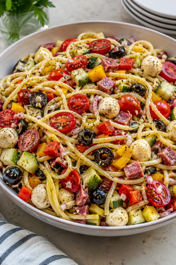 Italian spaghetti salad with colorful vegetables, herbs, vinaigrette, and protein-rich toppings