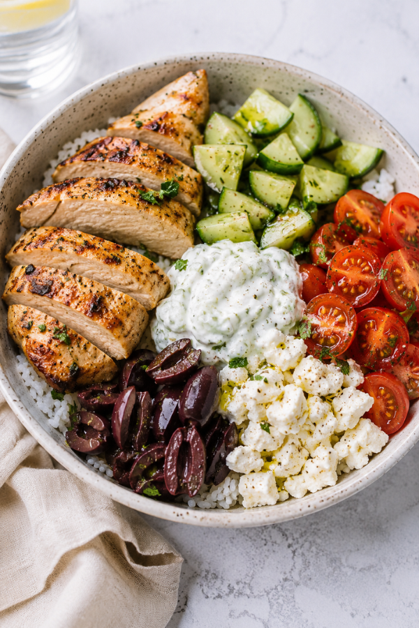 Greek chicken bowl as a summer high protein anti-inflammatory dinner with grilled chicken, quinoa, cucumber, tomatoes, feta, and yogurt sauce