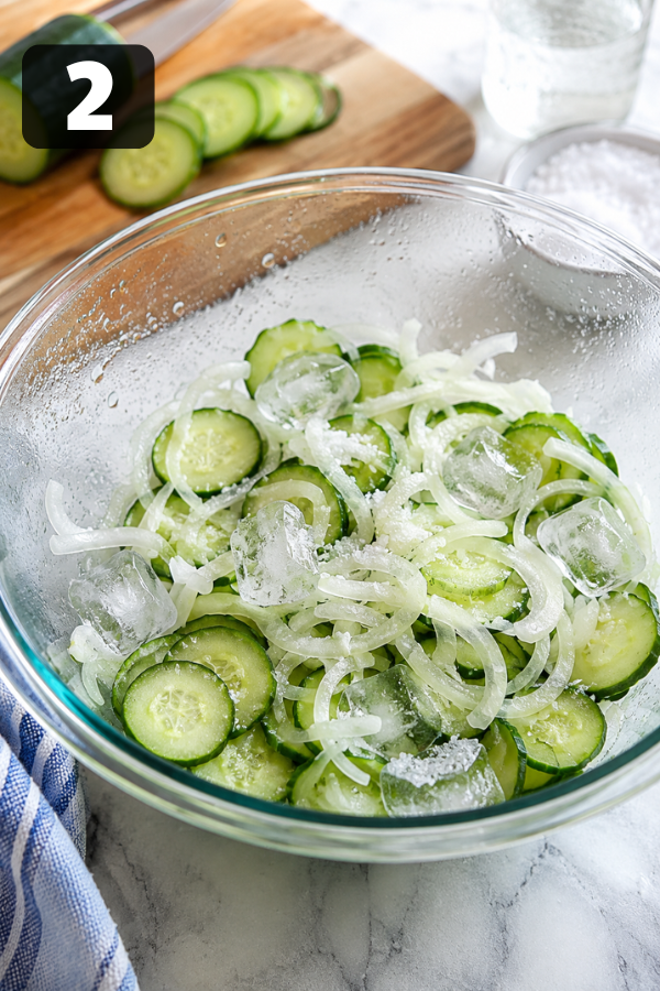 Sliced cucumbers and onions covered with pickling salt and ice to keep them crisp before canning