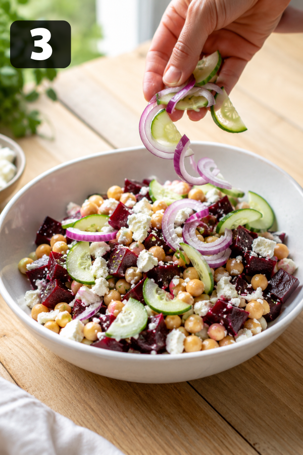 Cucumber and red onion being added to chickpeas and beets for fresh crunch texture
