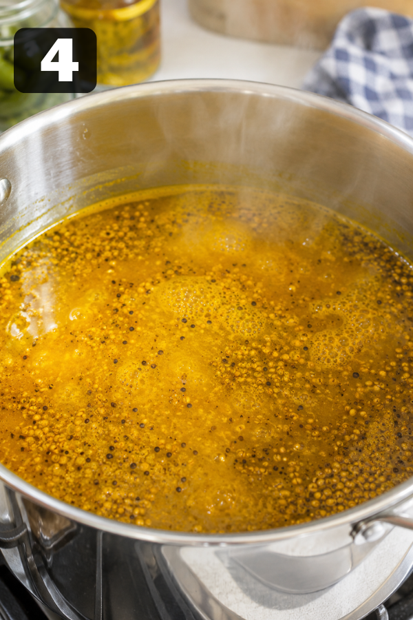 Sweet and tangy pickle brine boiling with vinegar, sugar, mustard seed, celery seed, and turmeric