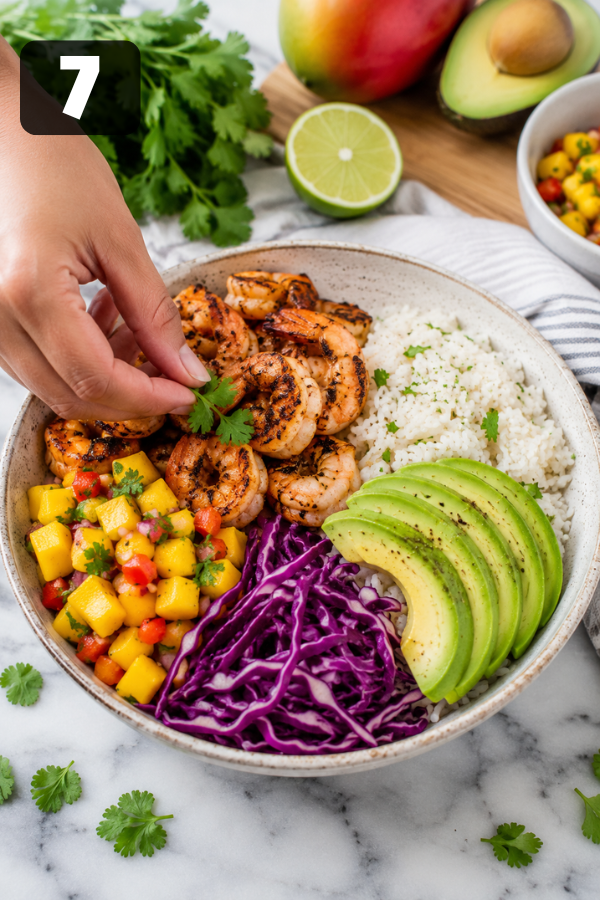 Finished shrimp avocado bowl assembled with rice, grilled shrimp, mango salsa, cabbage, avocado, lime, and sauce.