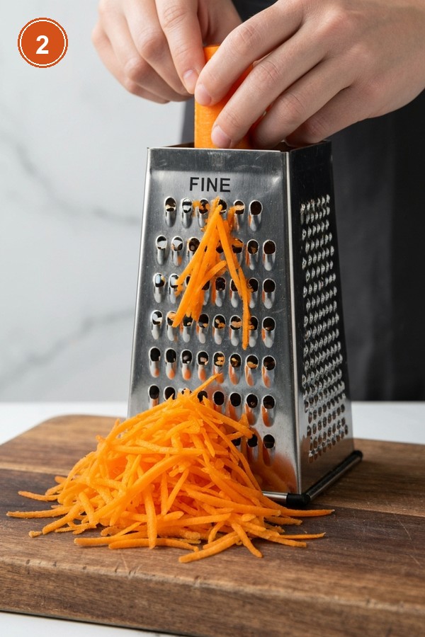 Step 2: Grating fresh carrots on fine side of box grater on wooden cutting board