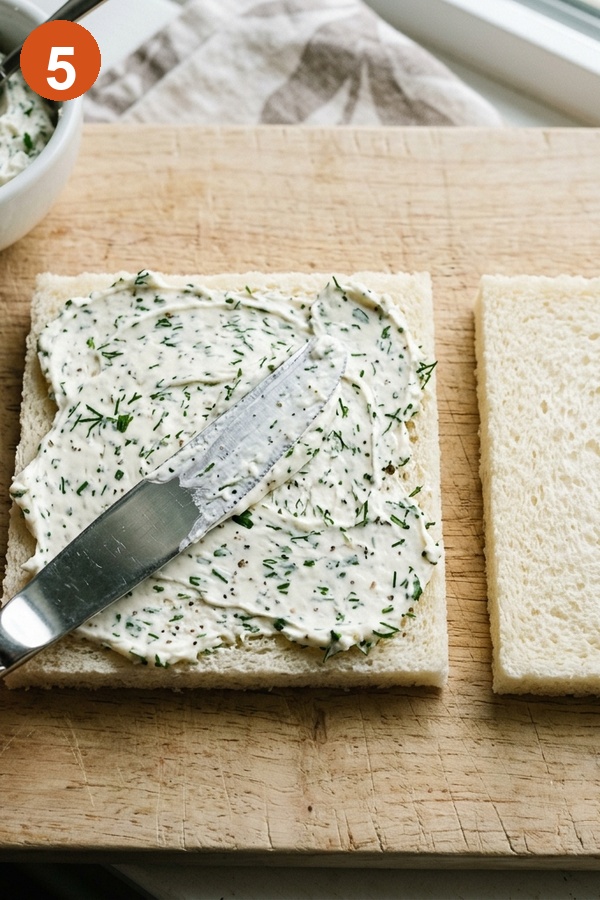 spreading cream cheese to bread edges for cucumber sandwich barrier