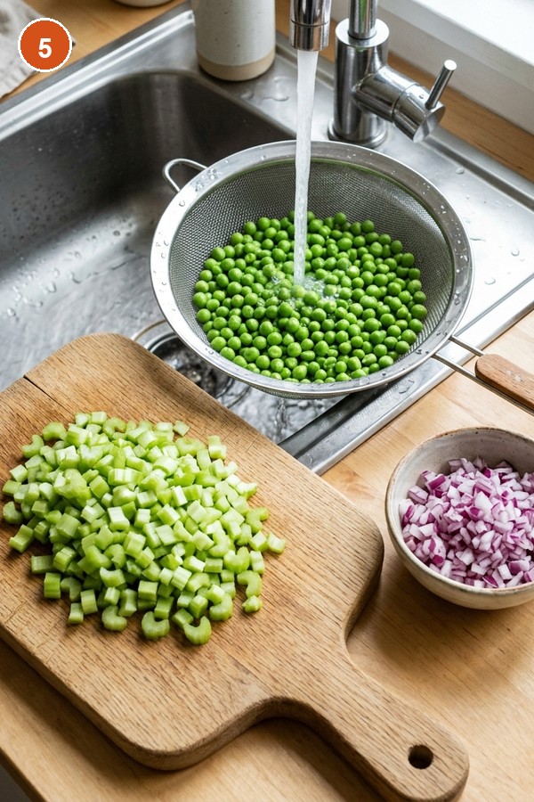 dicing celery red onion and thawing peas for seafood pasta salad